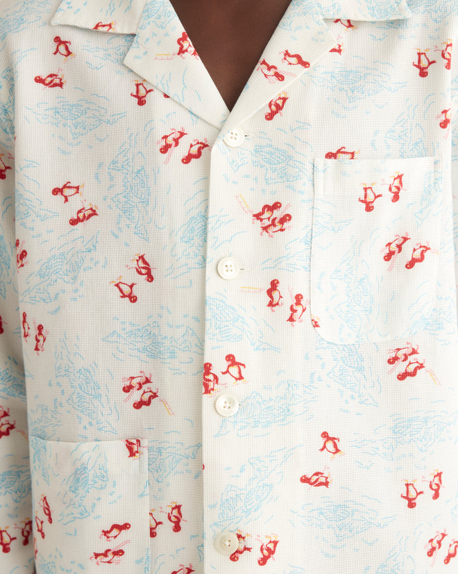 Close-up of a vintage Skiing Penguins Long Sleeve Shirt from the 1950s-1960s, crafted in cotton with a red skier print and blue map designs, featuring white buttons and a front pocket.