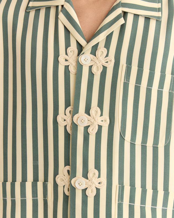 Close-up of the Soda Stripe Trillium Shirt, a green and cream vertically striped silk piece with floral knot buttons, charming frog closures, and two pockets. Rich in 1940s-inspired elegance, it embodies timeless style.
