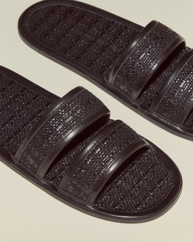 The Solid Summer Slides feature a black woven texture and double straps, delivering effortless style—perfect for summer, shown here on a beige background.