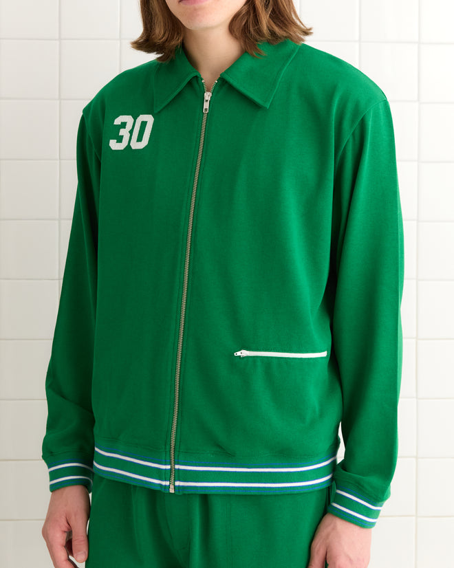 Against a tiled backdrop, someone wears the Sophomore Jacket, a green 1950s-inspired zip-up with the number 30 on the front.