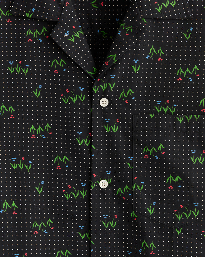 The Spring Grass Short Sleeve Shirt - XS/S features a black base with white polka dots and budding flowers in green, red, and blue, crafted from unique deadstock fabric and finished with white buttons.