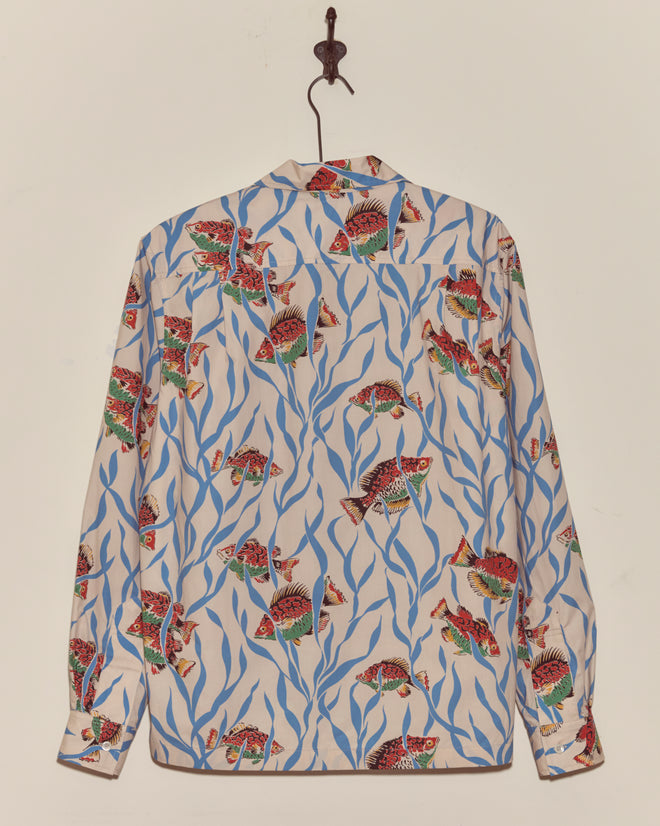 Swimmers Long Sleeve Shirt in blue, featuring a vibrant fish and seaweed pattern, displayed on a wall hook.
