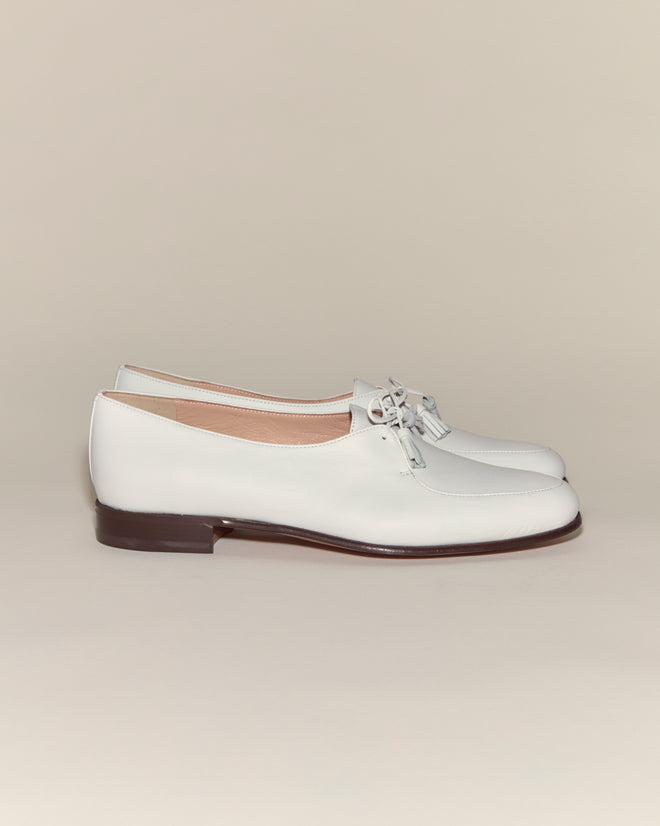 Tassel Shoes - White: Vintage white loafers with tasseled ties, minimalist design, and low dark brown heels displayed on a neutral background.