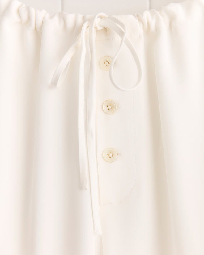 Close-up of Trillium Pajama Pants - Cream: 1950s-inspired silk design with an adjustable drawstring waist and three front buttons.