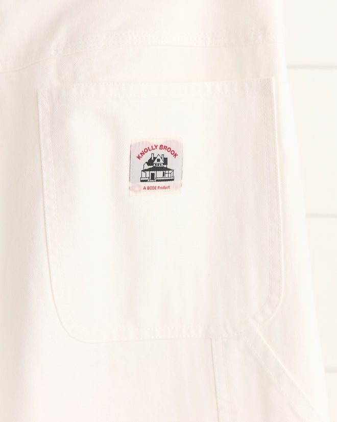 Close-up of a white fabric pocket on Twill Knolly Brook Trousers, featuring a small rectangular label with a house logo and