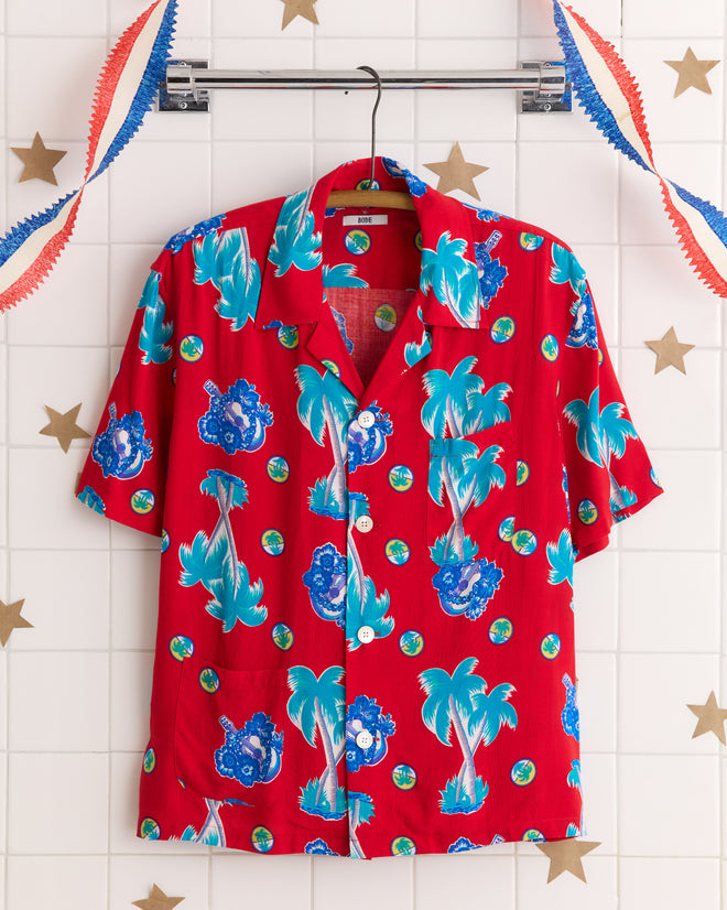 The Ukulele Tune Shirt features blue tropical designs on red fabric made from rare deadstock yardage, displayed against a white tiled wall with star decorations.
