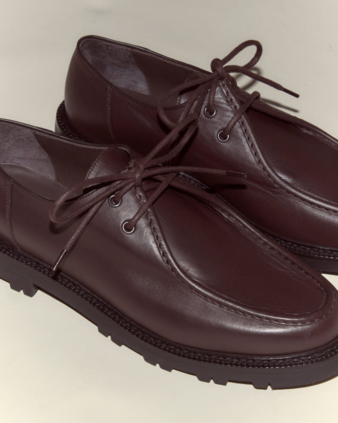 The University Shoes - Brown are Italian-crafted from supple calf leather in a rich dark brown, featuring a lace-up design and thick rubber soles against a light background.