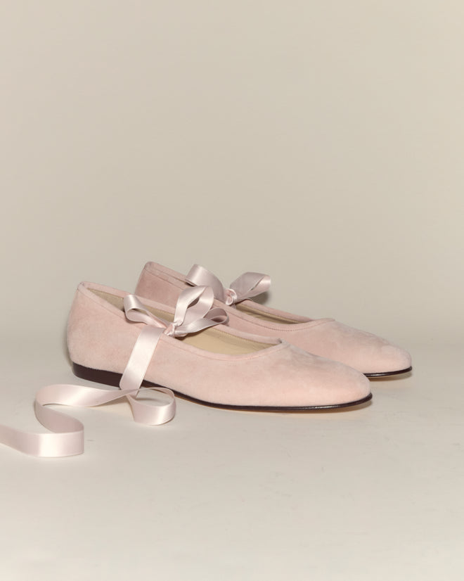 The Musette Flats - Pink are pale pink suede ballet shoes with satin ribbon ties, displayed on a plain light background for a timeless, graceful look.