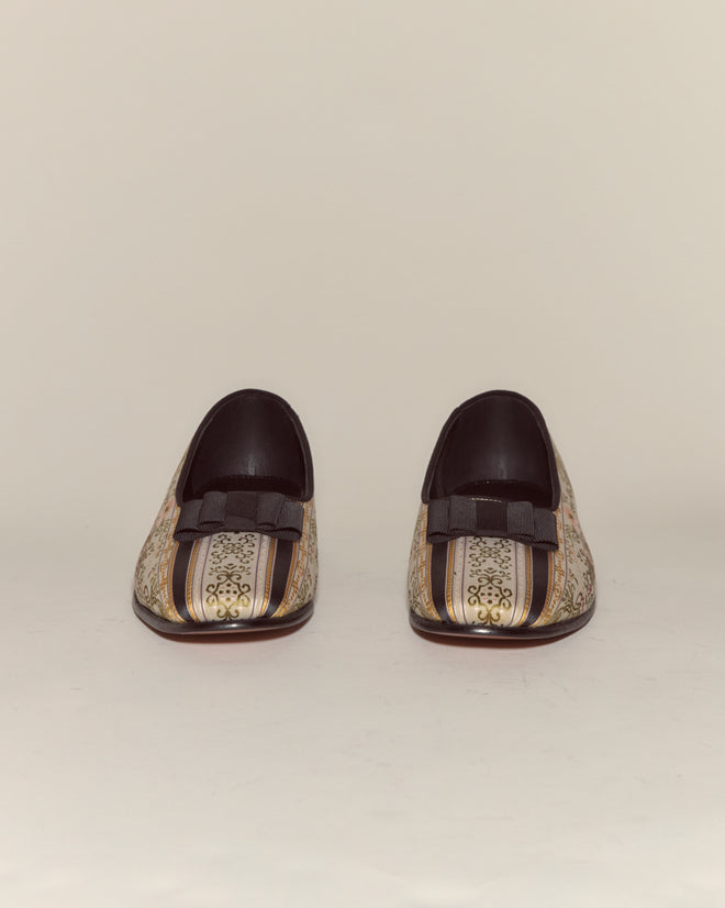 Floret Brocade Opera Pumps: Elegant men's evening slippers with gold patterns, black bows, and pointed toes, inspired by classic opera pumps, shown on a plain background.