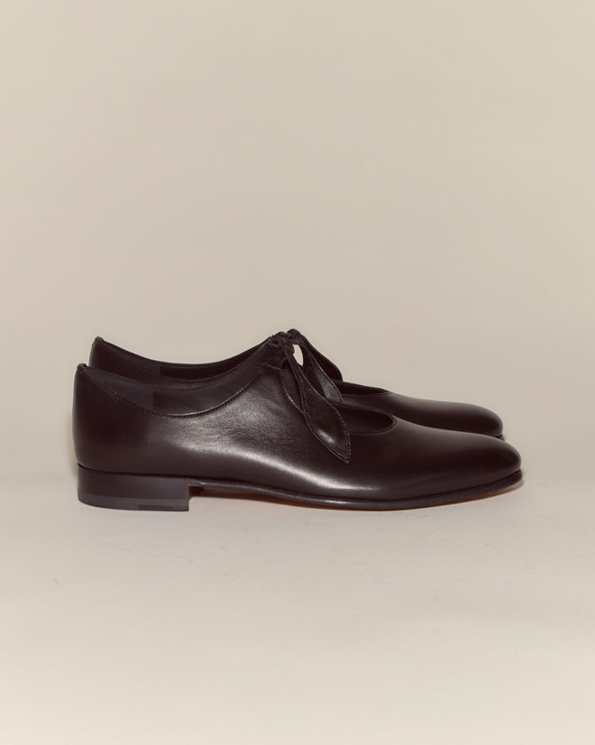 The Verbena Shoes - Black are Italian-made leather shoes with ribbon laces, shown on a neutral background.