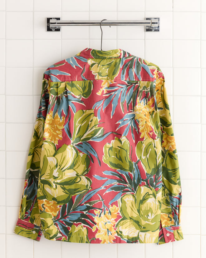 The Watercolor Foliage Long Sleeve Shirt - L, crafted from unique deadstock fabric, hangs on a hanger against a white tiled wall.