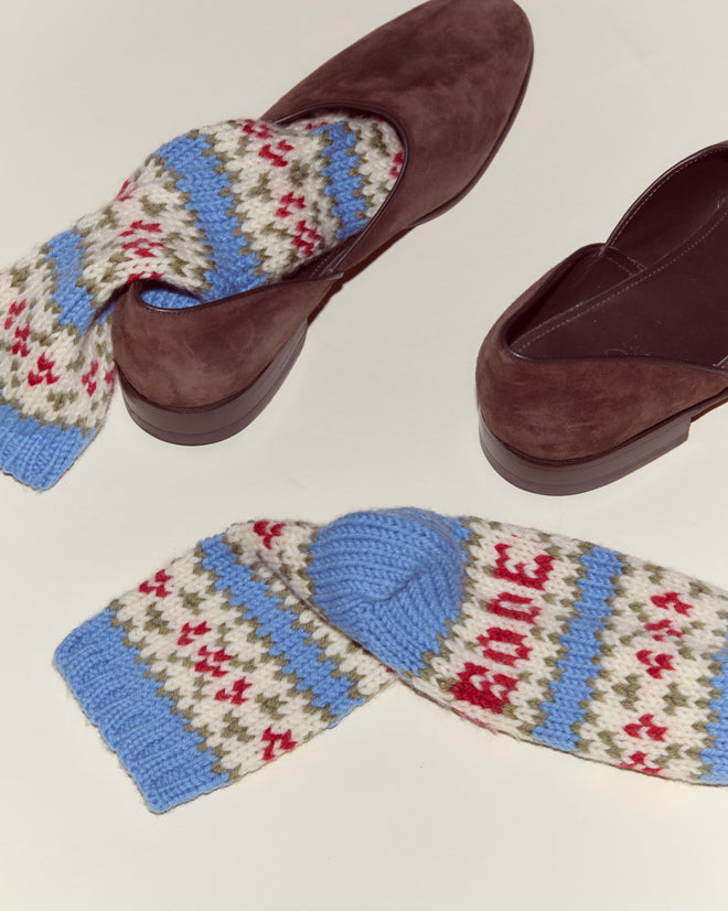 Two brown shoes with Wedgewood Socks in blue, red, and white vintage-inspired design tucked inside each shoe on a light background.