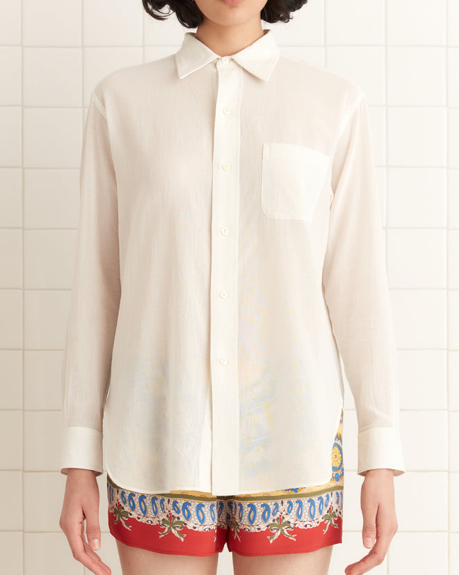 Person wearing a Voile Murray Shirt in cream and red printed shorts, standing against a tiled wall.
