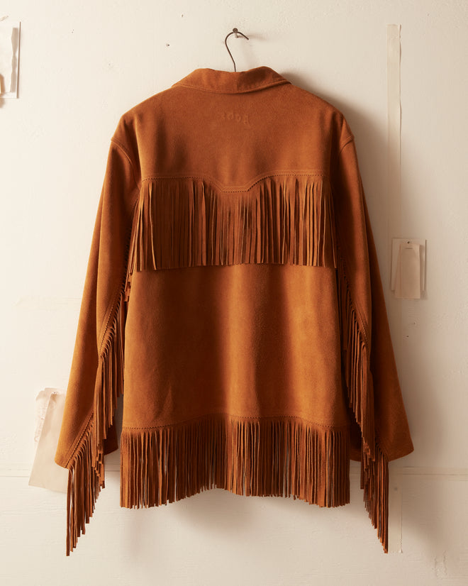 The Appalachian Jacket - Camel is a brown suede jacket with long fringe details on the back, sleeves, and hem—a classic Western piece perfect for style enthusiasts.