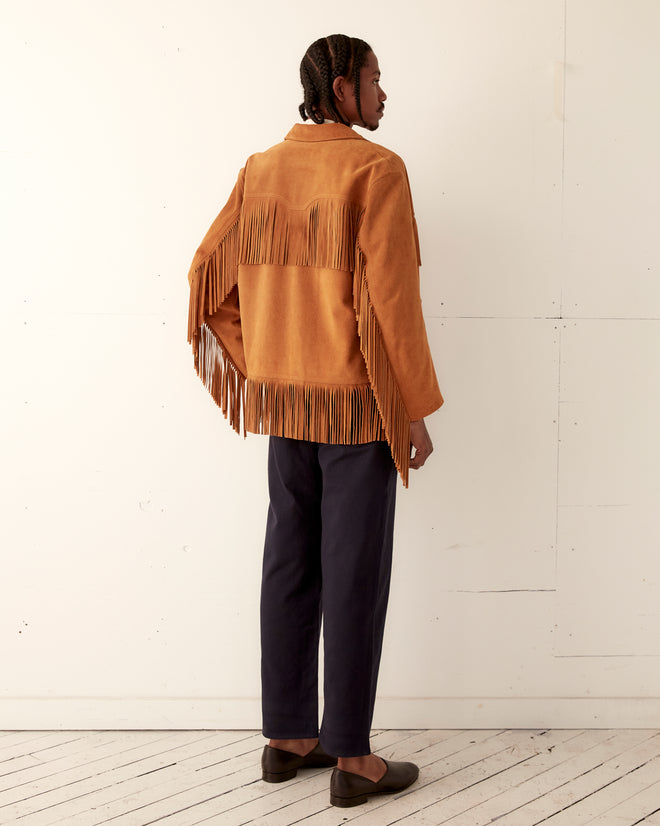 Person standing sideways in the Appalachian Jacket - Camel, paired with black pants and loafers, against a white wall.