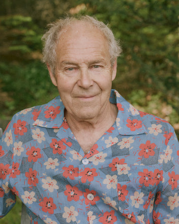 An older man with gray hair wears the Geo Poppy Long Sleeve Shirt, standing outdoors with greenery in the background.