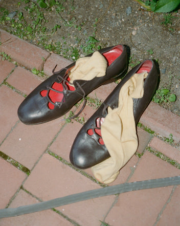 A pair of County Clare Shoes - Brown with tan socks inside, made from premium Napa leather, resting on a brick path.
