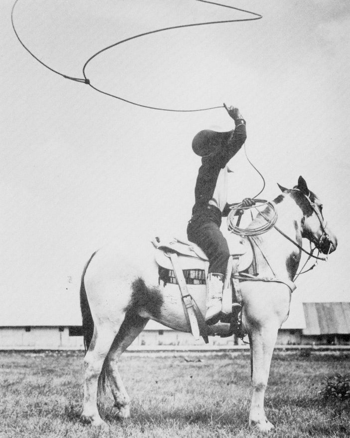 Historic photo of a lassoing performer at a rodeo.
