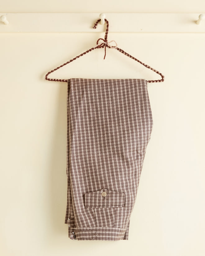 Acorn Check Trousers - 30, folded on a braided hanger and displayed against a cream-colored wall.