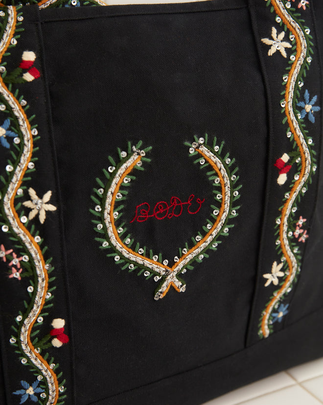 Alpineflower Tote, a black bag adorned with wildflower patterns and colorful embroidered straps, featuring 