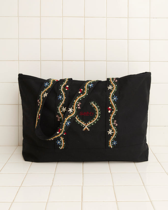 Alpineflower Tote, a black bag adorned with wildflower patterns and colorful embroidered straps, featuring 