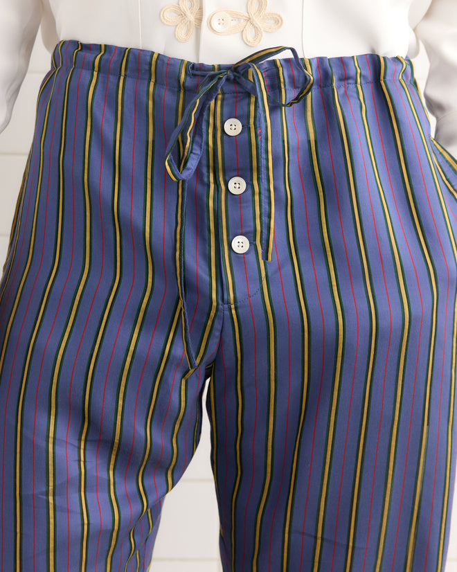 Model wearing Alumni Stripe Pajama Pants in blue, featuring a vintage-inspired striped pattern, drawstring waist, and button details; shown from waist to mid-thigh.