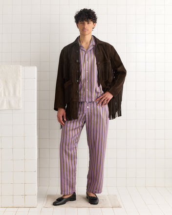 A person wearing striped pajamas and the Appalachian Jacket - Brown stands in a tiled room with white walls and floors.