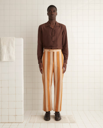 A person in a brown shirt and Awning Stripe Trousers, reminiscent of classic 1950s-1960s suiting, stands in a tiled room.