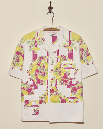 Banana Bunch Short Sleeve Shirt - L/XL: White short-sleeve shirt with a vibrant banana-themed pattern, inspired by vintage tablecloths, displayed on a hanger.