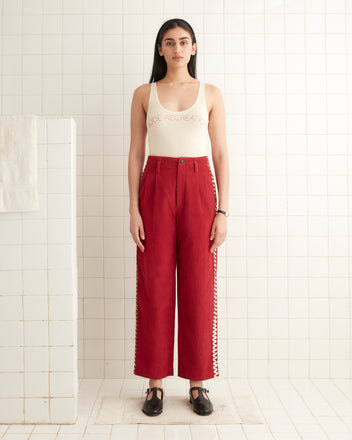 A person in a white tank top and Bandstand Murray Trousers stands in a tiled room.