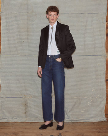 Man wearing suit jacket with dark-wash jeans.