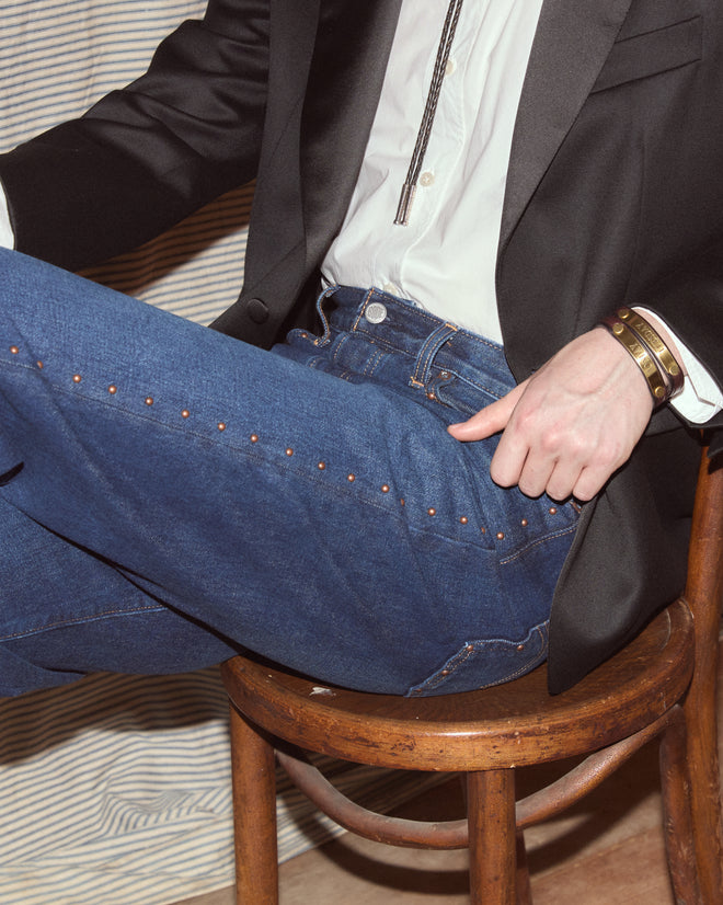 Man wearing suit jacket with dark-wash jeans.