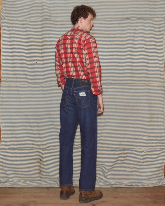 Man wearing plaid shirt with dark-wash jeans.