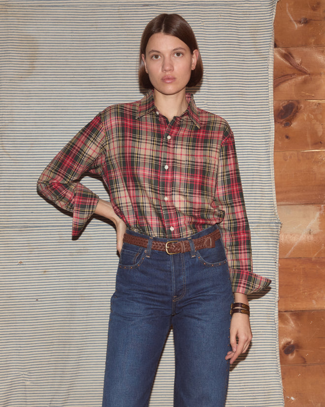 Woman wearing a plaid shirt with dark wash jeans and a brown belt