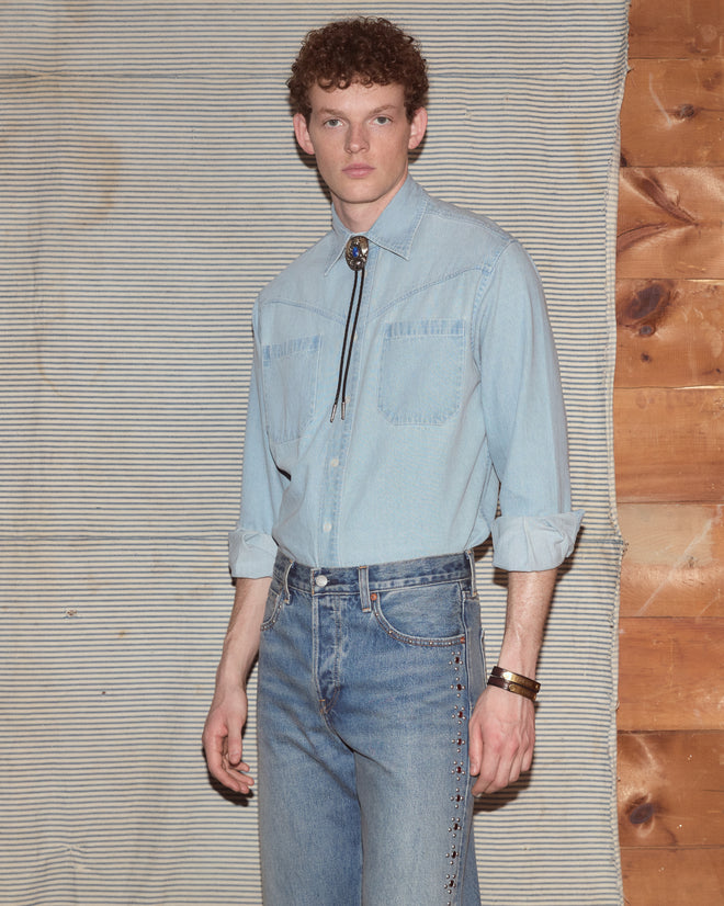 Man wearing light-wash jeans and a chambray shirt.