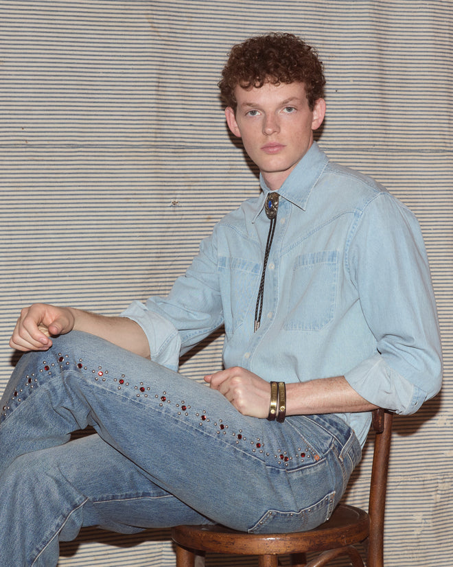 Man wearing light-wash jeans and a chambray shirt.
