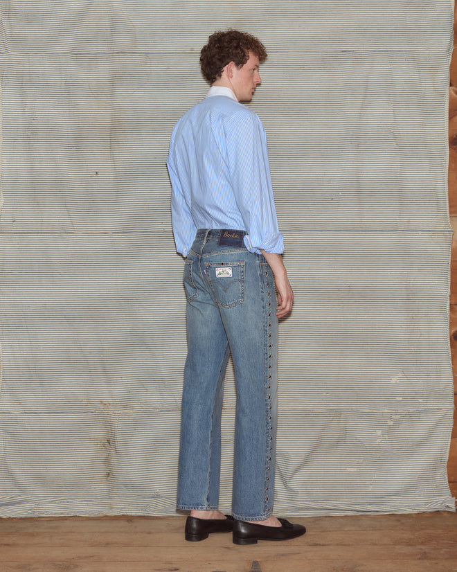Man wearing light-wash jeans and a poplin shirt.