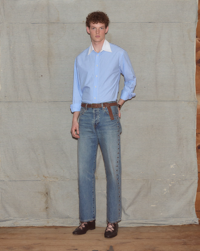 Man wearing light-wash jeans and a poplin shirt.
