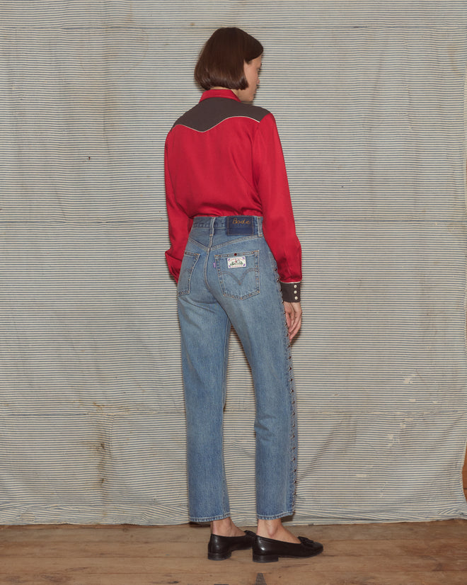 Woman wearing a red and black blouse with light wash jeans
