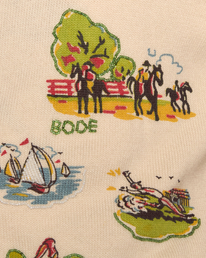 Beaded Camp Cardigan features illustrations of people, horses, boats, and trees with "BODE" on beige fabric, evoking the cozy nostalgia of a summer camp sweater.