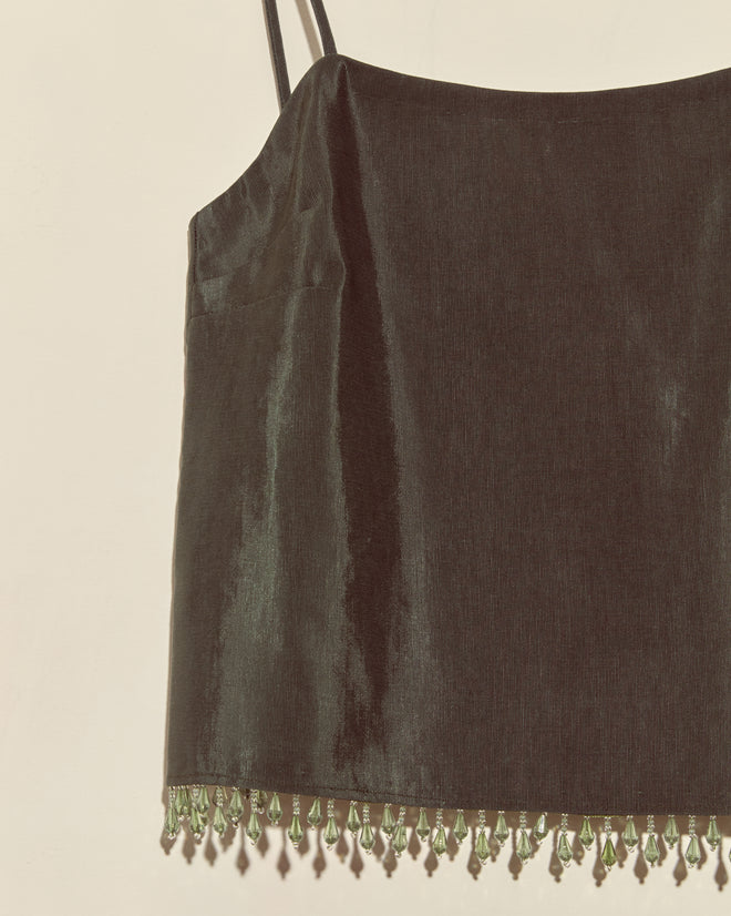 The Beaded Hemlock Tank - S is a black satin camisole with thin straps and green droplet beads forming a fringe along the hem, inspired by vintage style.