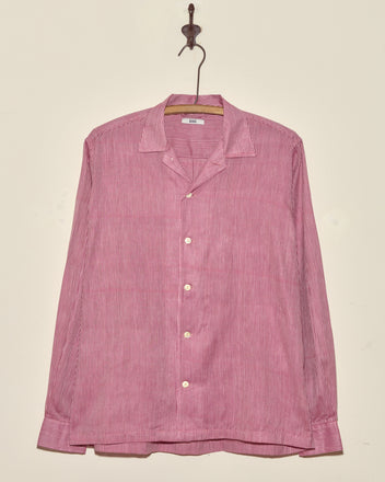 A Berry Creme Stripe Shirt in size S/M with vintage red and white stripes and long sleeves hangs on a hook against a plain wall.