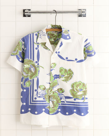 Blueberry Polka Dot Shirt - S/M: a short-sleeve white vintage shirt with blue and green polka dot pattern, hanging on a rack against a tiled wall.