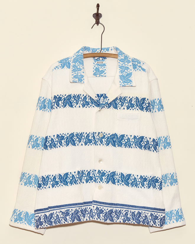 The Blue Ivy Overshirt - XL features white jacquard fabric with light and dark blue horizontal floral patterns, displayed on a wooden hanger.
