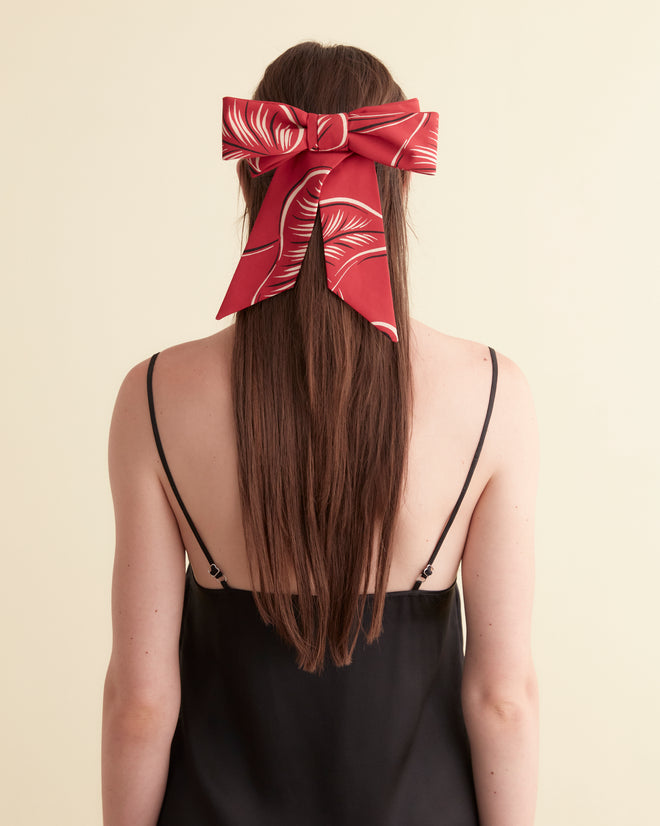 Introducing the Creeping Begonia Bow Barrette: a stunning accessory that showcases a striking red and white pattern on a light textured background. Carefully crafted as part of our viscose accessories line, it features a touch of midcentury botanical pattern for an extra dash of charm.