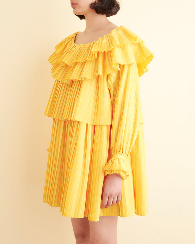 Close-up of the Brunch Dress - Yellow, showcasing cascading tiers and pleated layers, crafted from recycled polyester.