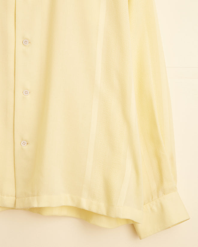 The Cadmium Yellow Line Shirt - XL/XXL, a light yellow long-sleeve button-up featuring custom textiles, is hanging on a white wall hook.