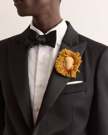 Man in a black tuxedo with a Calder Leo Brooch on his lapel, reminiscent of Alexander Calder jewelry, wearing a bowtie.