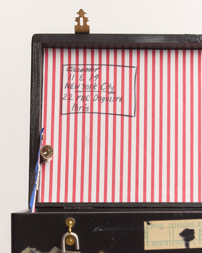 The Calder Suitcase Box features a lid with red and white stripes, a handwritten address, and attached small objects, evoking the playful spirit of Calder’s Circus now admired at the Whitney Museum of American Art.
