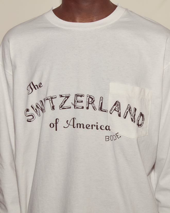 The Campground Long Sleeve is a 100% cotton white shirt featuring "The Switzerland of America Bode" in black above the chest pocket—ideal for a classic summer camp look.